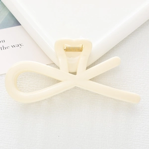 Close-up of a minimalist cream-white hollow hair claw clip with a golden spring mechanism
