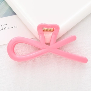Detailed macro view of a pink heart-shaped hair claw clip with golden metal spring
