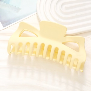 Macro view of a large matte cream hair claw clip with a stylish geometric cutout design