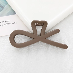 Detail view of a brown heart-shaped hollow hair clip on a minimalist white background