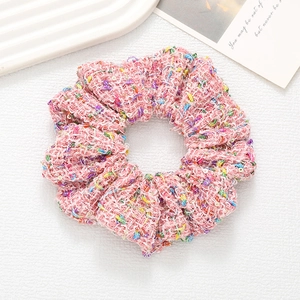 Detailed texture of pink tweed scrunchie with colorful threads and sequins