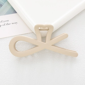Close-up of matte beige bow hair clip with heart detail on a white background