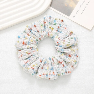 Detail of tweed hair scrunchie with colorful threads, sequins and soft thick texture
