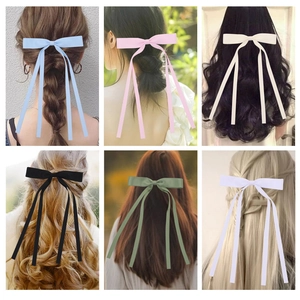 Detail showing six colorful long ribbon bow hair clips on various hairstyles and hair colors