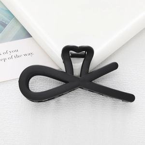 Detail of a matte black hair claw clip featuring an elegant heart and bow design