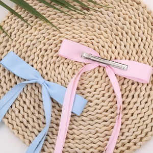 Elegant bow hair clips with long ribbons in pink and blue on a woven background