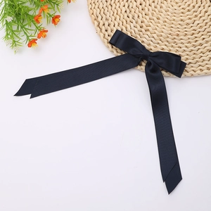 Detail of elegant navy satin double layer bow with long streamers on a straw hat accessory