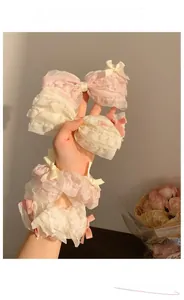 Dettaglio degli elastici per capelli in pizzo rosa e beige stile balletto con fiocchetti