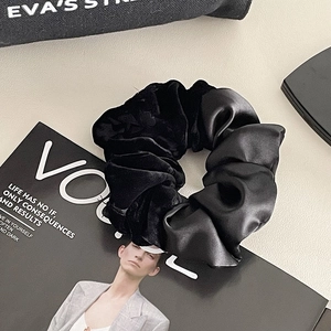 Detail of black scrunchie showing dual texture of matte velvet and glossy satin fabrics