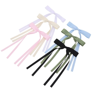 Detail of six colorful long ribbon bow hair clips in satin fabric on white background