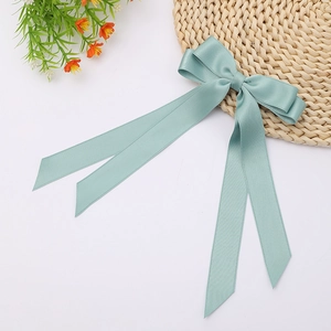 Detailed view of a mint green double-layered satin bow hairclip with long flowing ribbons