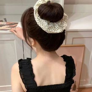 Polka dot fabric hair scrunchie shown in a cream and black pattern on a high bun hairstyle