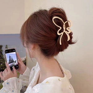 Elegant hollow butterfly hair claw in gold metal worn by a model in home setting