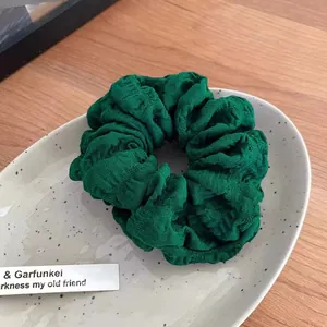 Detaillierte Makroansicht der dunkelgrünen Stoffstruktur des großen modischen Scrunchies
