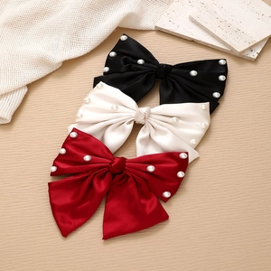 Three-piece satin bow hair clip set with pearl accents in black, cream, and deep red