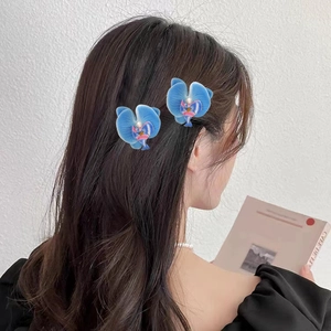Pinces à cheveux orchidée bleue avec perles sur cheveux longs pour un look de printemps