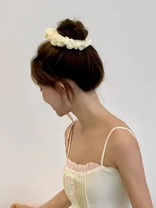 Großaufnahme eines cremefarbenen Oversize-Strick-Scrunchie am Haaransatz