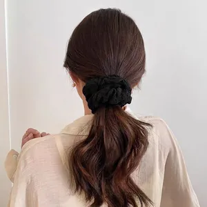 Detailansicht eines großen schwarzen Scrunchie-Zopfgummis mit feiner Spitzenstruktur