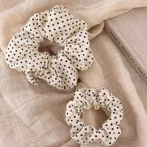 Detailed close-up of cream polka dot fabric scrunchies in two different sizes