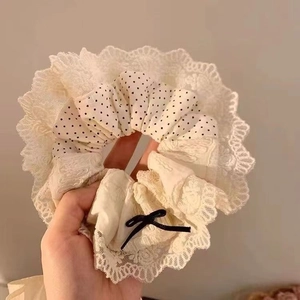 Dettaglio dell'elastico in pizzo crema a pois con un fiocco decorativo in seta nera
