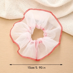 Détail d'un chouchou en tulle blanc de 15 cm avec bords cousus rouges sur fond texturé