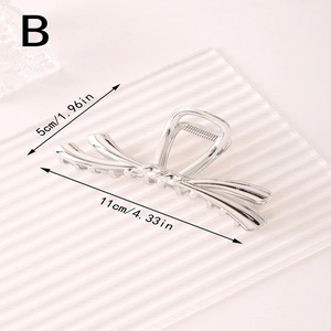 Détail d'une pince à cheveux en métal argenté avec motif nœud et dimensions de 11cm
