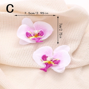Vue détaillée de pinces à cheveux orchidées roses avec perles sur tissu beige texturé