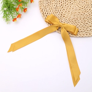 Detail of a silky ginger yellow double-layered ribbon bow hairclip with long tails