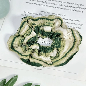 Detail of green and white tie-dye ink pattern on a pleated fabric oversized scrunchie