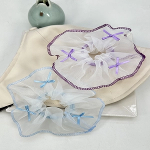 Détail de deux chouchous en organza avec rubans sur un chapeau, texture en maille