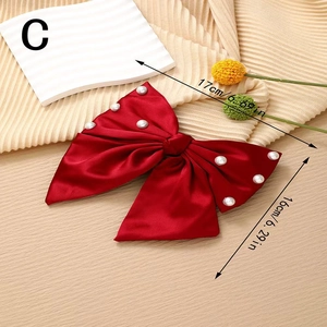 Detail showing red satin bow hair clip with white pearls and size dimensions in cm