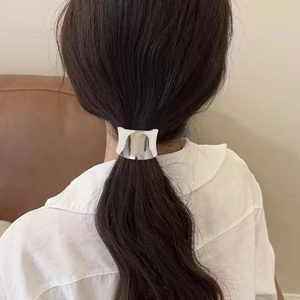 Close-up of a sleek silver ponytail cuff on a woman's low ponytail in a cozy indoor setting