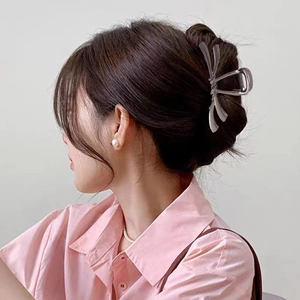 Détail d'une pince à cheveux élégante en métal gris avec nœud sur une coiffure relevée