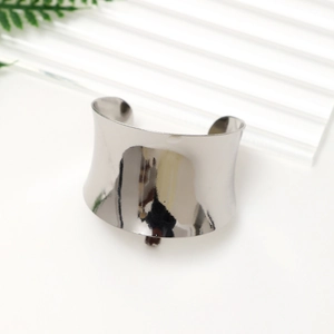 Detail of a wide open silver bangle with high-gloss mirror finish and concave design