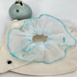 Détail d'un chouchou en maille bleu clair avec nœuds en ruban vert menthe sur chapeau