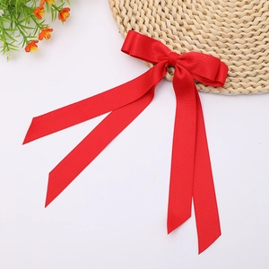 Detail of red satin bow hair clip with long streamers on a decorative white background