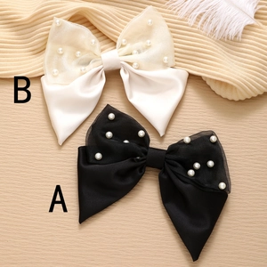 Close-up of elegant satin and organza bow hair clips with pearls in black and ivory