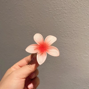 Détail de la pince à cheveux fleur de frangipanier en résine dégradé rose et paillettes fines