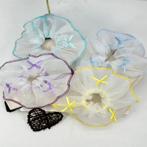 Détail de chouchous en organza avec petits nœuds en violet, jaune et bleu pastel