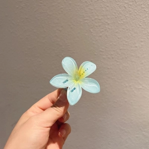 Détail de la pince à cheveux fleur de frangipanier bleu clair au centre jaune