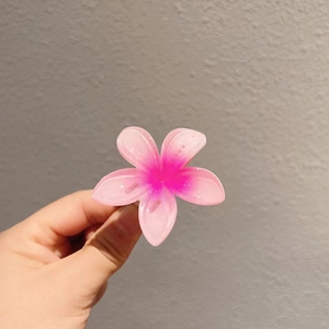 Vue détaillée d'une pince à cheveux frangipanier rose bonbon avec une finition résine