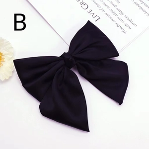 Detail of elegant black satin bow hair clip with textured ribbon and spring fastener