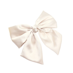 Close-up of a creamy white satin bow hair clip with elegant pearlescent finish