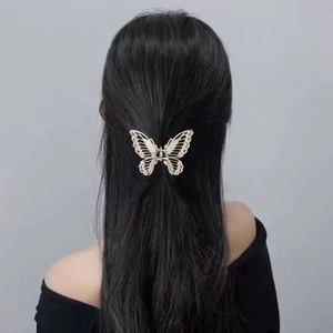 Detailed close-up of a golden hollow butterfly hair claw clip worn on long black hair