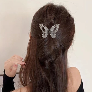Silver hollow butterfly hair claw clip shown in a semi-tied hairstyle on a model
