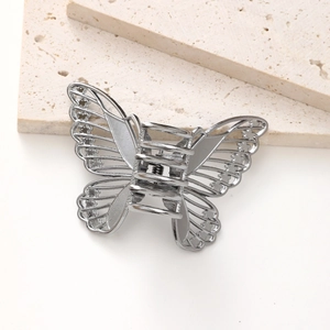 Macro detail of silver alloy butterfly hair claw featuring hollowed-out metal wing design