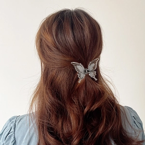 Dettaglio del fermaglio per capelli a farfalla in metallo argento con design minimalista
