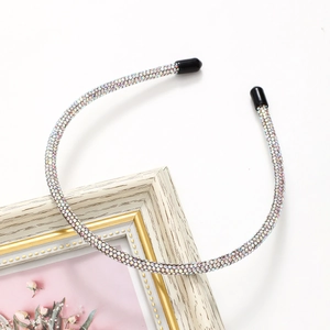 Elegant thin silver headband with shimmering rhinestones on vintage white picture frame