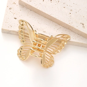 Close-up of golden alloy butterfly hair claw clip with intricate hollow carved patterns