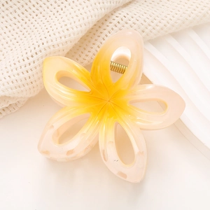 Gros plan sur la pince à cheveux fleur de frangipanier avec dégradé jaune et rose